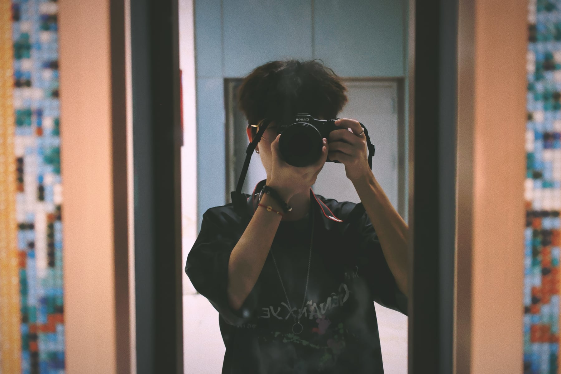 Rayce Zhang holding a camera in a mirror self-portrait.